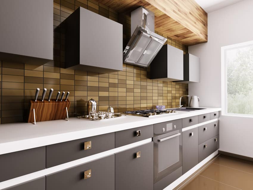 Modern kitchen with copper tile backsplash, white countertop, black cabinets, stove, range hood, oven, and window