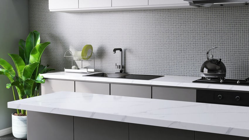 Modern kitchen with square mosaic tile backsplash, countertop, sink, stove, and faucet