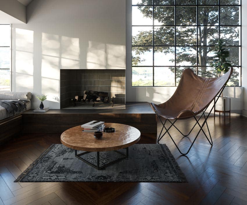 Modern living room with tripolina chair, rug, coffee table, fireplace, and windows