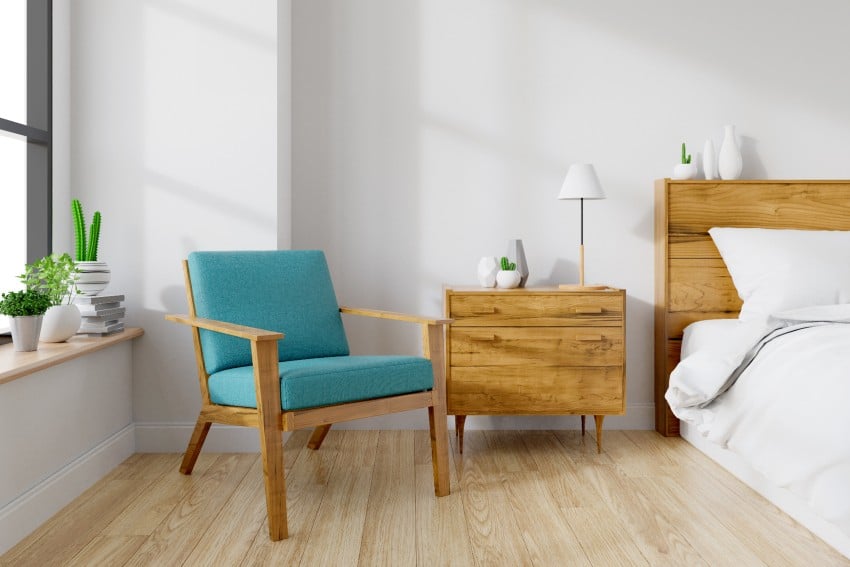 Modern mid century and vintage interior of bedroom with blue lounge chair, wood bedside table and bed 