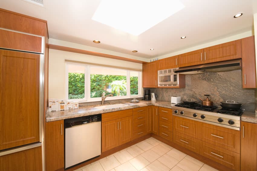 Modern rustic kitchen with pressed wood cabinets, countertop, granite backsplash, tile flooring, stove, and windows