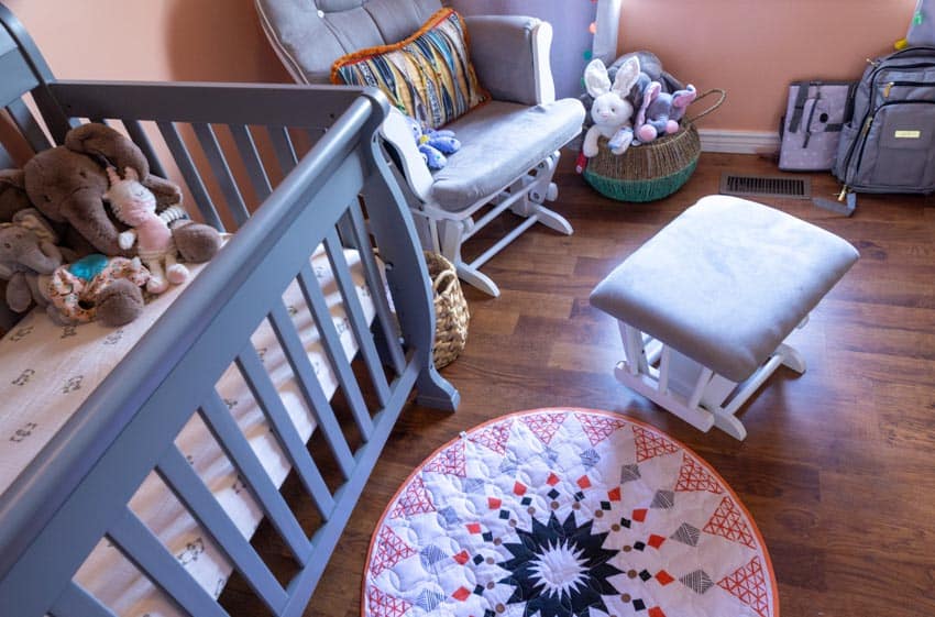Nursery with glider chair, ottoman, crib, and wood floors