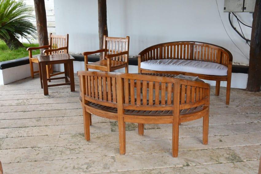 Outdoor patio with couch, chairs, stone tile flooring and white walls