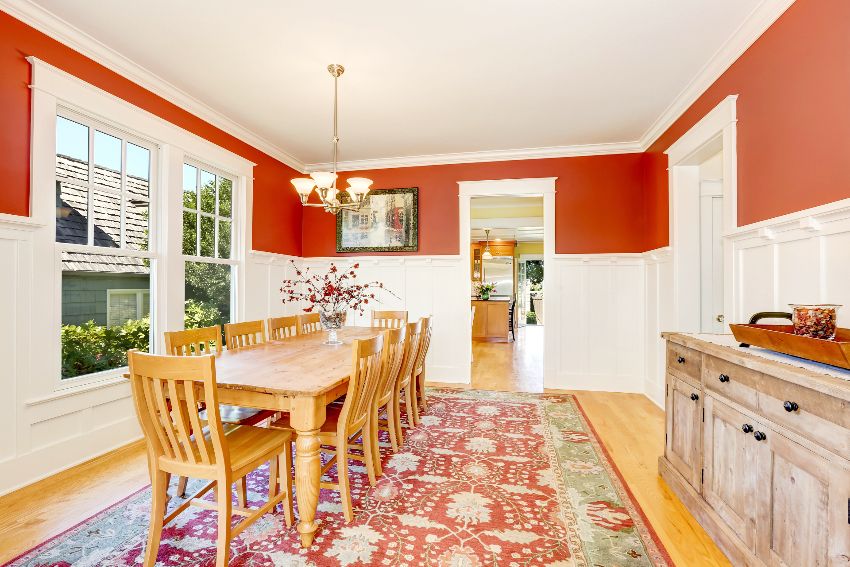 Room with red wall, white painted wainscoting and wooden dining set