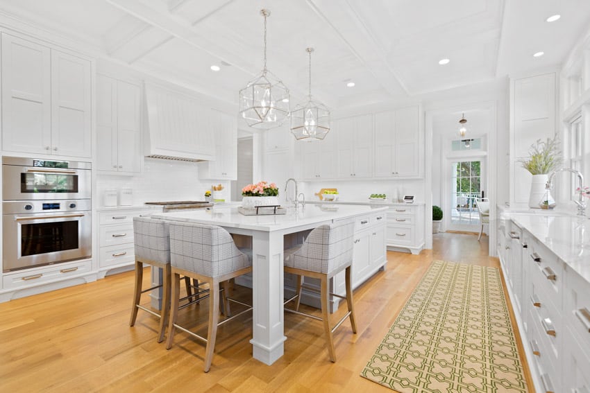 Kitchen with white cabinets, island, chairs, wood flooring, pendant lights, and ceiling lighting fixtures