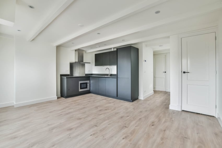 White ceiling and walls, L-shape kitchen with faucet and pine wood floors