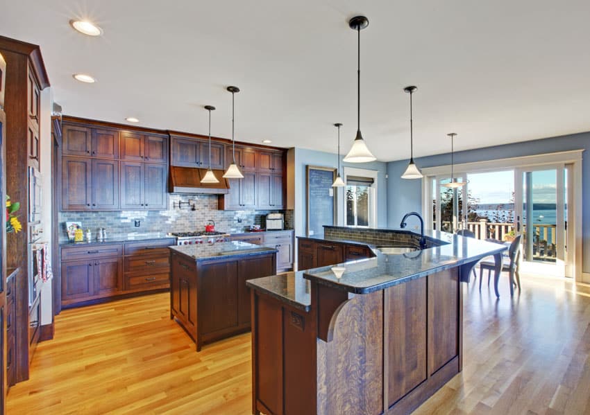 Remodeled traditional kitchen with bar counter, island, backsplash, wood flooring, cabinets, countertop, and pendant lights