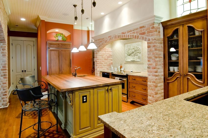 Kitchen with wood countertop, high chairs and brick surround