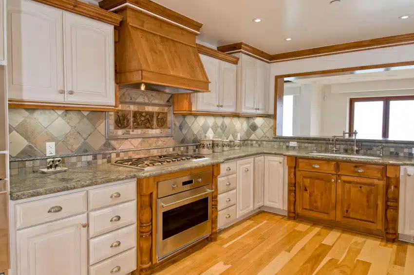 Rustic kitchen with white cabinets, square diamond tile backsplash, countertop, range hood, oven, stove, and window