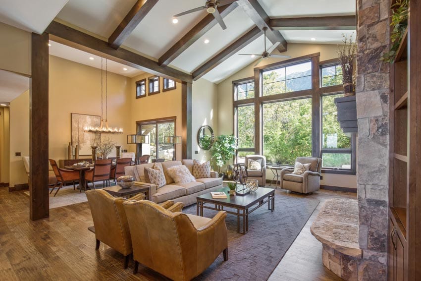 Exposed ceiling beams ceiling fan, and glass windows in a rustic style home