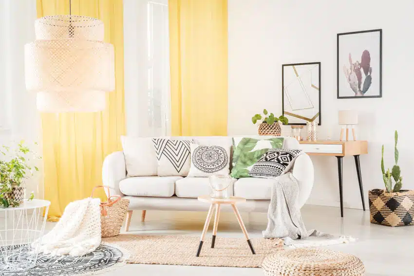 Scandanavian living room with white walls, bright yellow colored curtains, sofa, coffee table, console table, and pendant lights