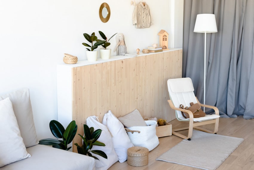 Scandinavian living room with pine wood cabinet, chair, lamp, and indoor plants