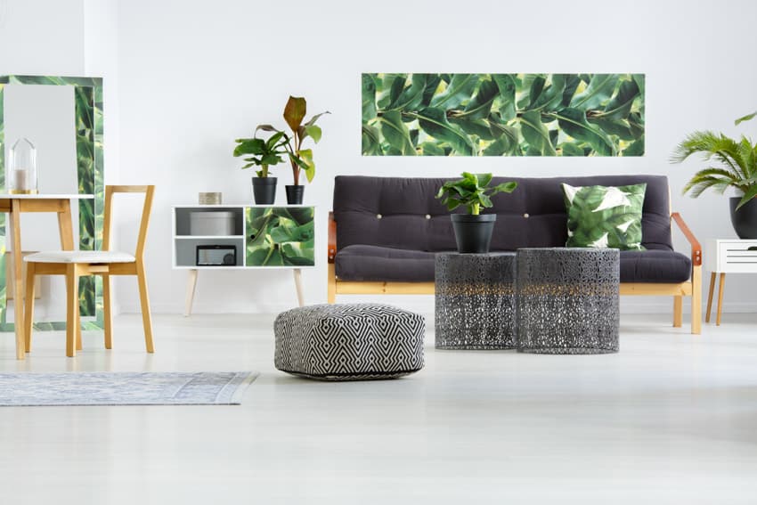 Scandinavian living room with pouf, cushioned sofa, chairs, and indoor plants
