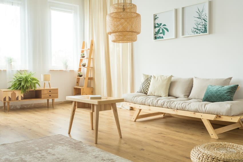Scandinavian living room with rubberwood coffee table, sofa, ladder, pendant light, wood floor, window, and curtain