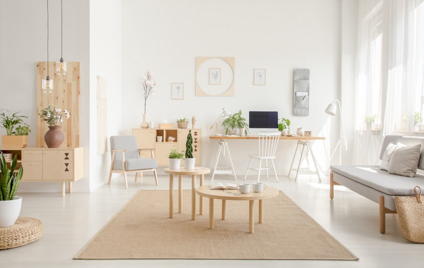 Scandinavian living room with work space, desk, pine wood coffee table, chairs, couch, and window curtains