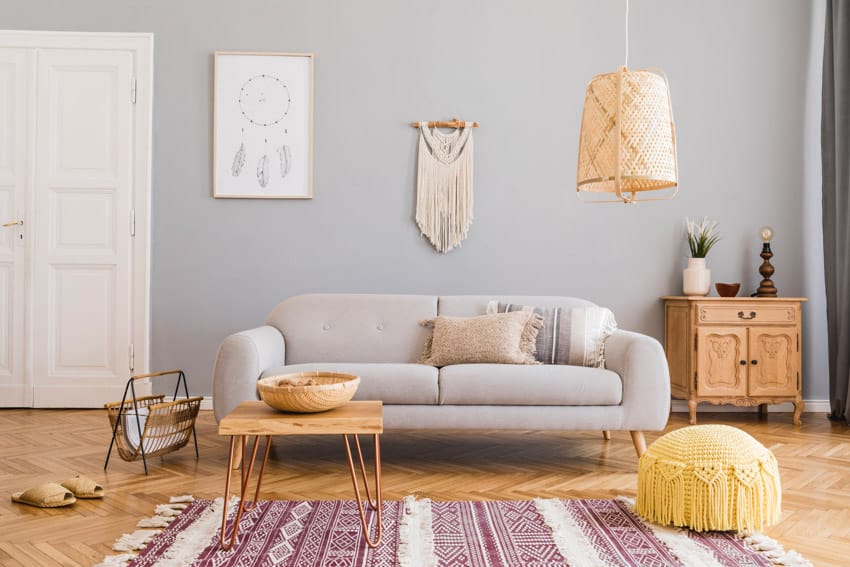 Simple living room with gray couch, coffee table, yellow pouf, small dresser, cabinet, pendant light, rug, and floor