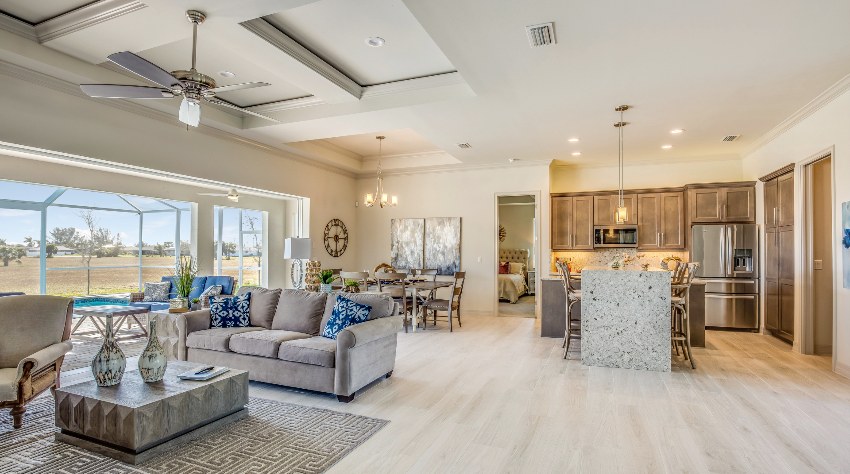 Open floor plan with beige tones, grey couch, coffered ceiling and vinyl flooring