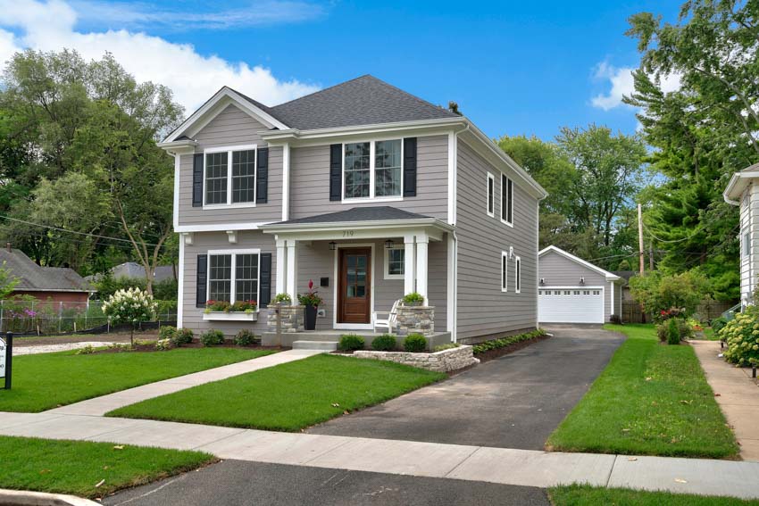 Suburban house with siding, windows, front door, windows, driveway, landscaped lawn, and walkway
