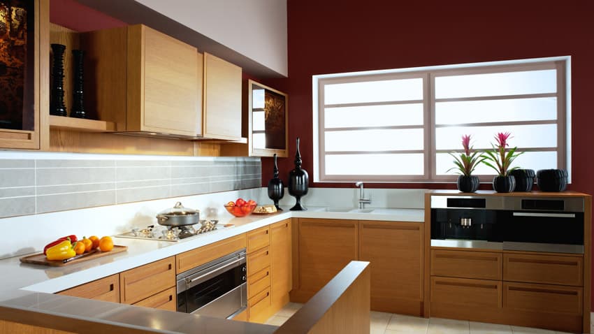 Traditional kitchen with pressed wood cabinets, countertop, tile backsplash, cabinets, oven, stove, and windows