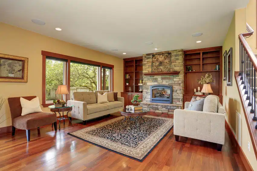 Traditional living room with cedar softwood flooring, rug, couch, chair, coffee table, shelves, fireplace, and windows