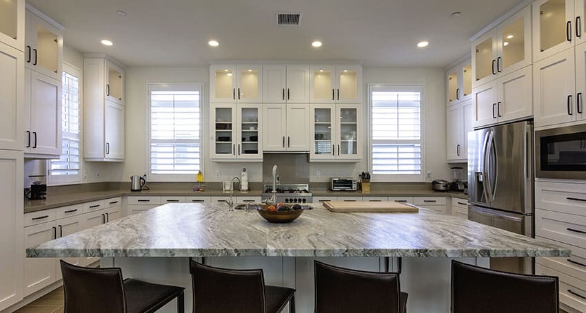 Kitchen with calcite countertop kitchen island upholstered stalls white cabinets single hung windows