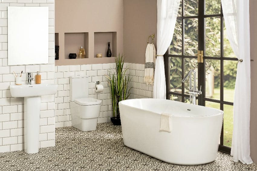 A beautiful bathroom interior with white bathtub, pedestal sink with a mirror and toilet