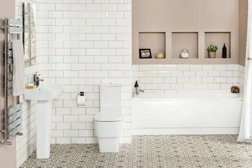 A beautiful classic bathroom interior with white bathtub, subway tiles wall, pedestal sink and patterned floor tiles