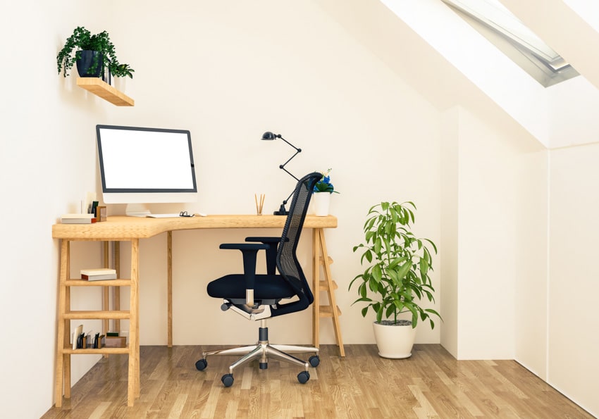 Attic office with desk, computer, office chair, indoor plants, skylight window, and wood floors