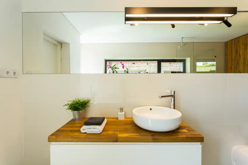 Bathroom with cedar countertop, basin sink, faucet, and vanity mirror