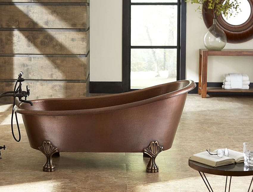 Bathroom with copper tub, clawfoot tub feet, mirror, window, and wood plank accent wall