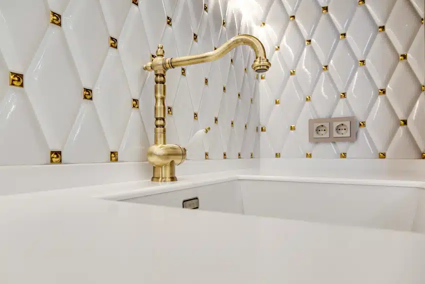 Bathroom with elongated tiles, faucet in gold finish and white sink