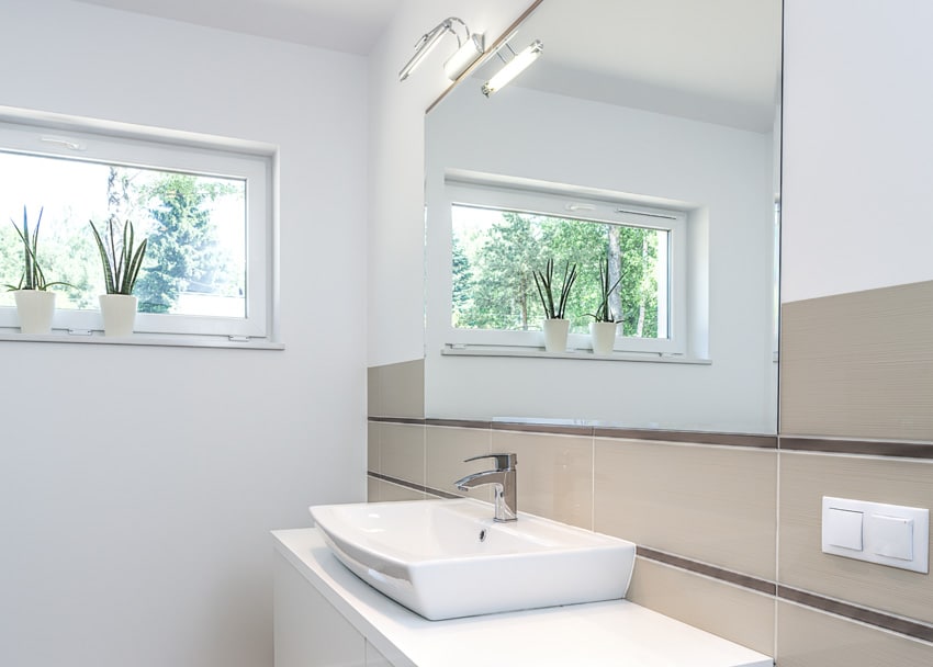 Bathroom with hopper window, sink, countertop, and vanity mirror