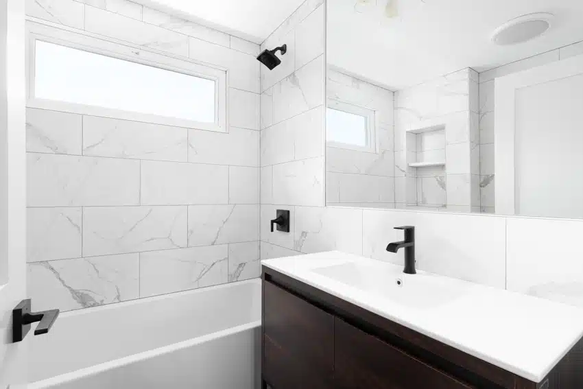 Bathroom with marble tile, frosted glass window and vanity mirror