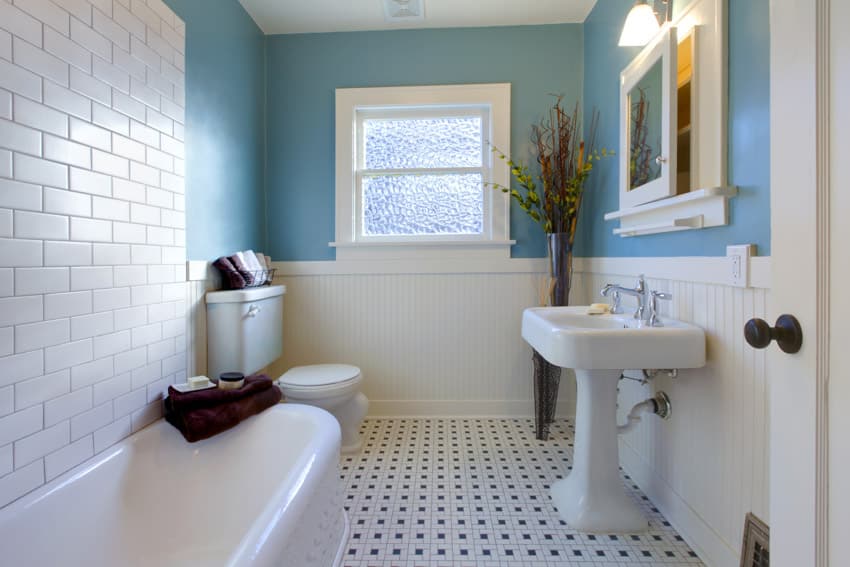 Bathroom with subway tile backsplash, tub, sink, mirror, tile flooring, toilet, and obscure glass window