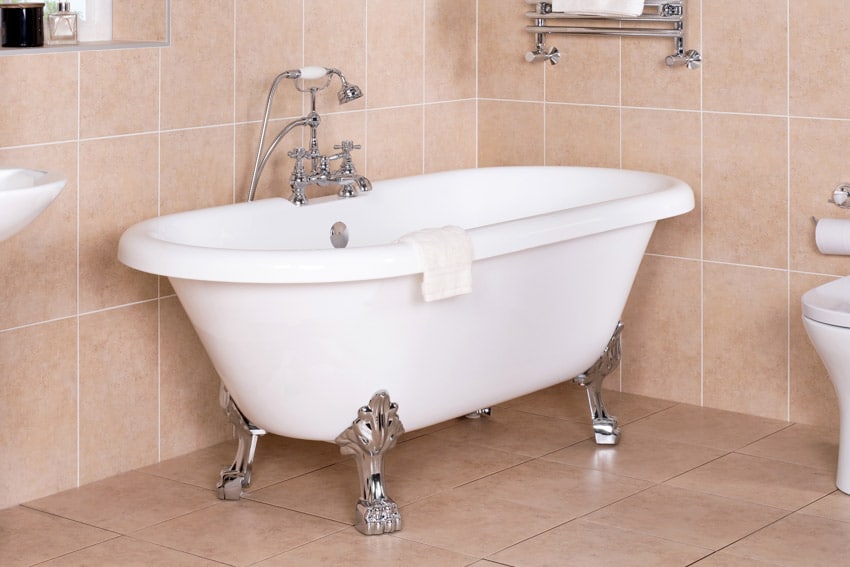 Bathroom with tile wall, floors, tub, faucet, and polished chrome clawfoot tub feet