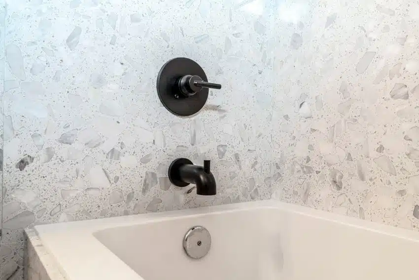Bathroom with tub, crushed glass wall, and matte black bathtub faucet