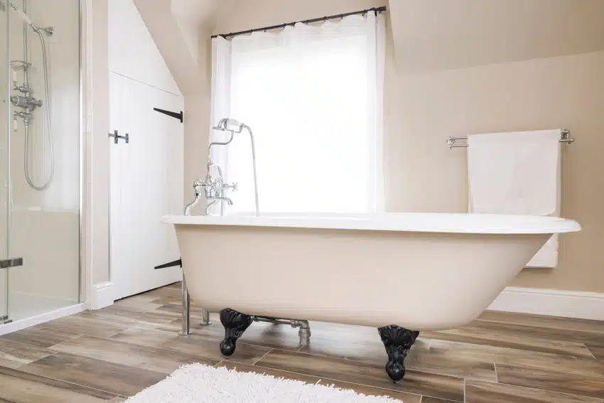 Bathroom with tub, wood floors, shower glass enclosure, window, curtain, towel holder, and ball and claw clawfoot tub feet
