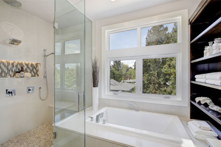 Bathroom with window, tub, shower area, glass door, and shelves