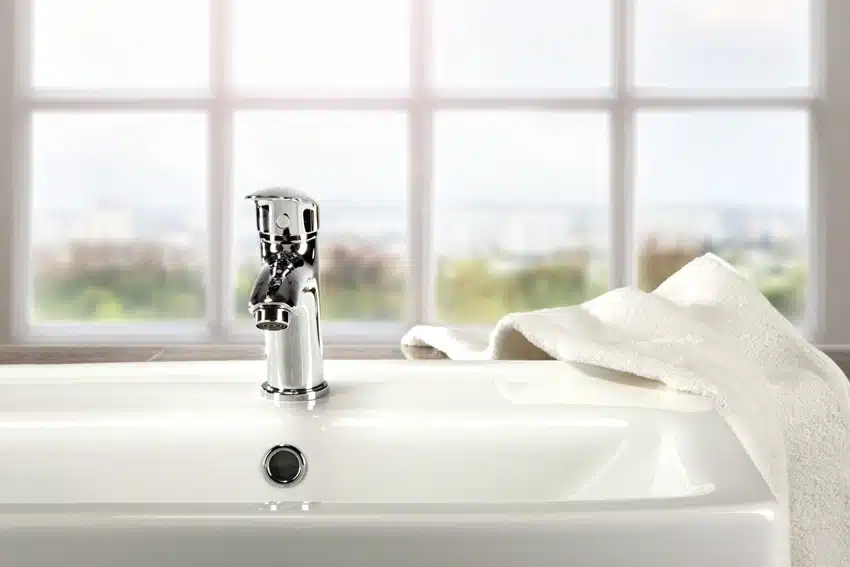 Bathtoom with chrome bathtub faucet, tub, and window