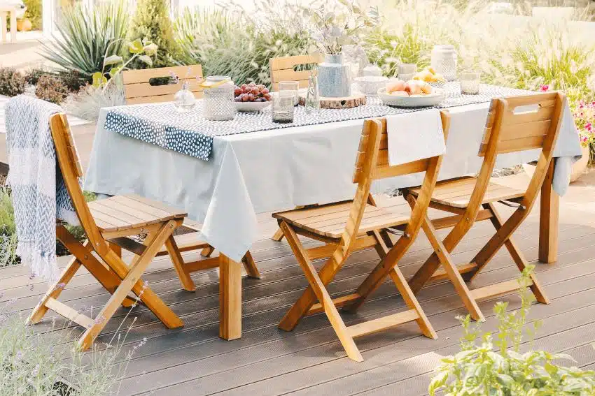 Beautiful dining table set with cotton tablecloth and wooden chairs on patio