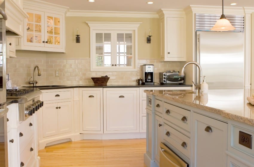 Beautiful kitchen with beige tones features wooden floors, island and colonial cabinets with cup handles