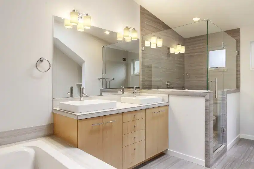 Beautiful masters bathroom features vanity pedestal sinks with cabinets and enclosed shower