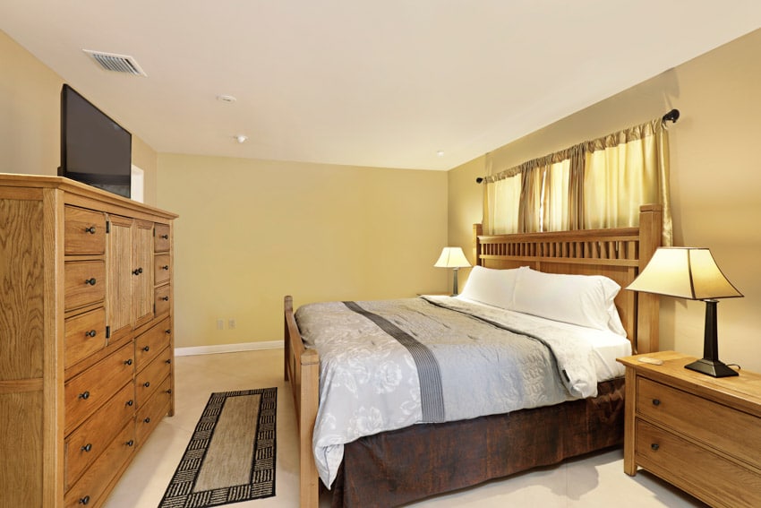 Bedroom with alder furniture, curtains with black rod, beige rug and recessed lighting
