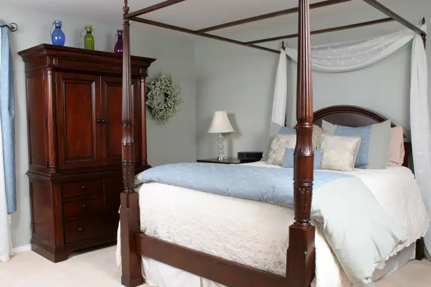 Bedroom with four poster bed, cherry wood cabinets and pillows