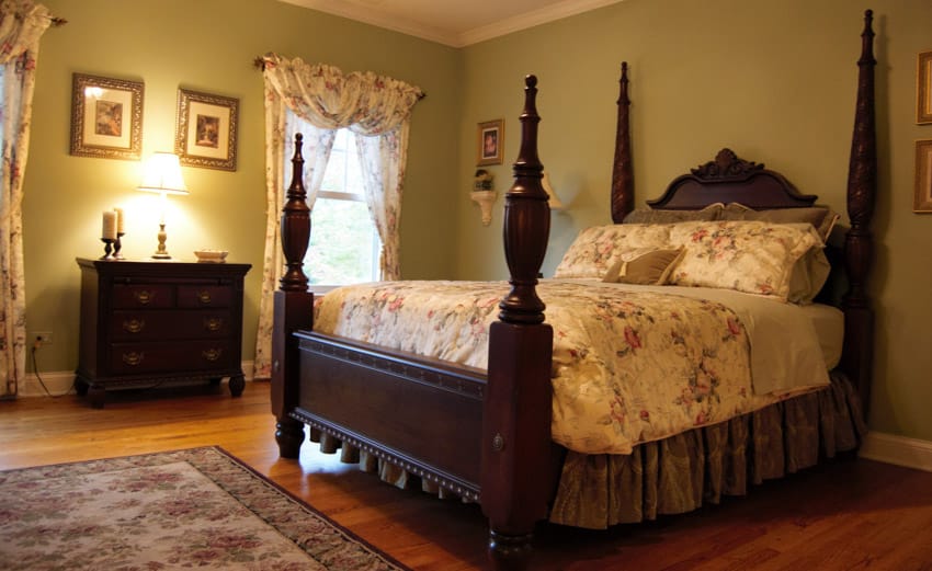 Bedroom with four poster mahogany bed, mattress, pillows, headboard, dresser, lamp, window, and curtains