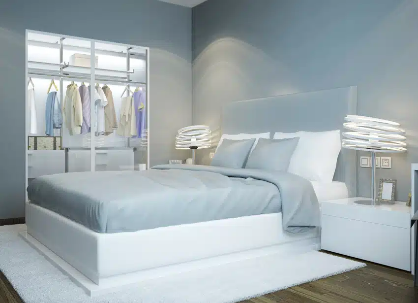 Bedroom with icy light blue wall, mattress, pillows, nightstand, lamps, and wardrobe closet