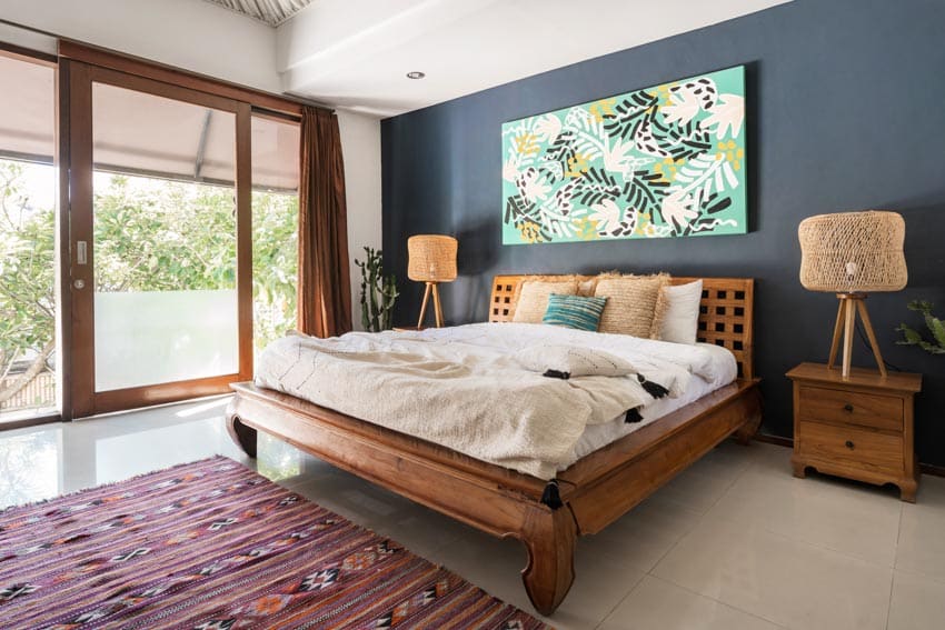 Bedroom with maple wood nightstands, lamps, rug, bedding, pillows, headboard, tile flooring, and glass door
