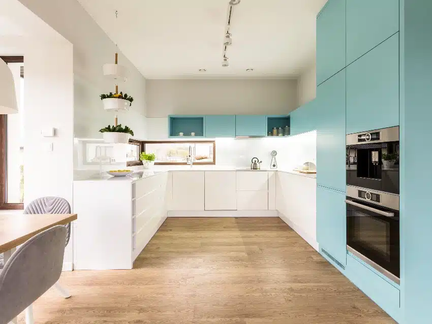 Blue and white cabinets in modern fitted kitchen interior with wooden floor