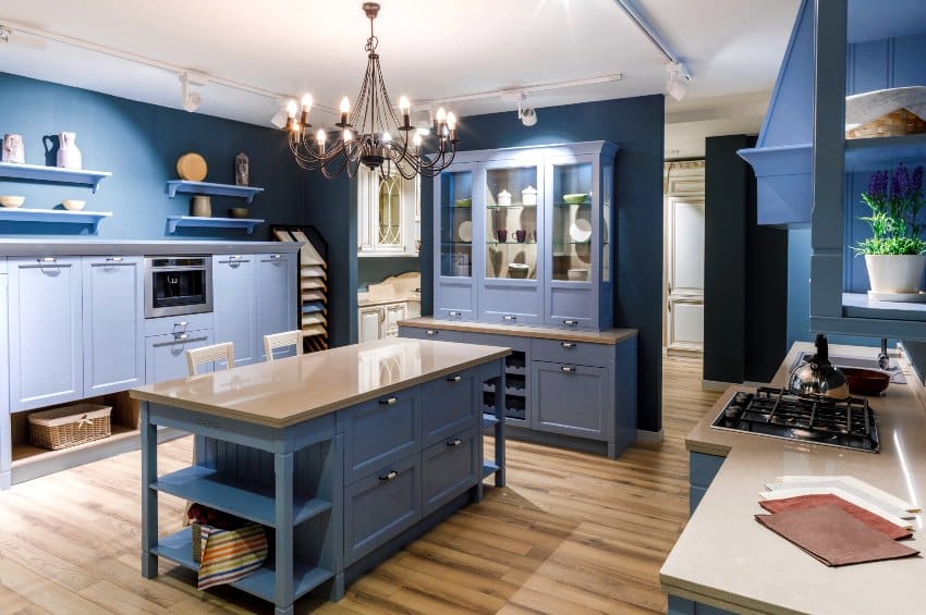 Blue country kitchen with freestanding cabinet island with legs, countertop floating shelves, stove wood floors and chandelier
