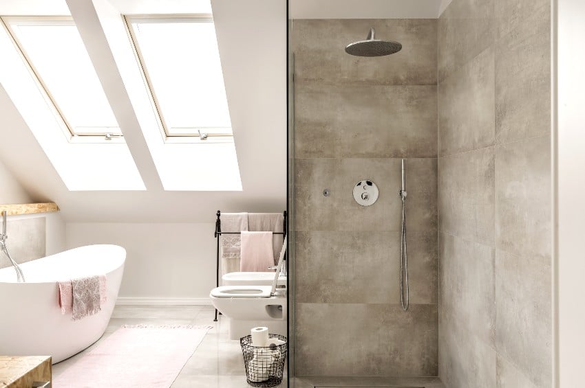 Bathroom with pedestal tub, sloped wall with windows and slate tiling